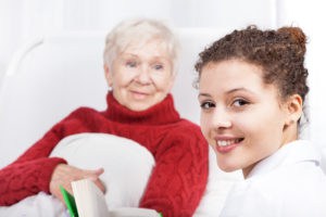 Female caregiver reading book with senior woman